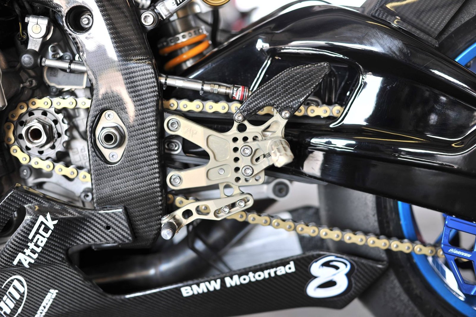 Close-up of race bike rearset, swingarm, and surrounding carbon fiber pieces